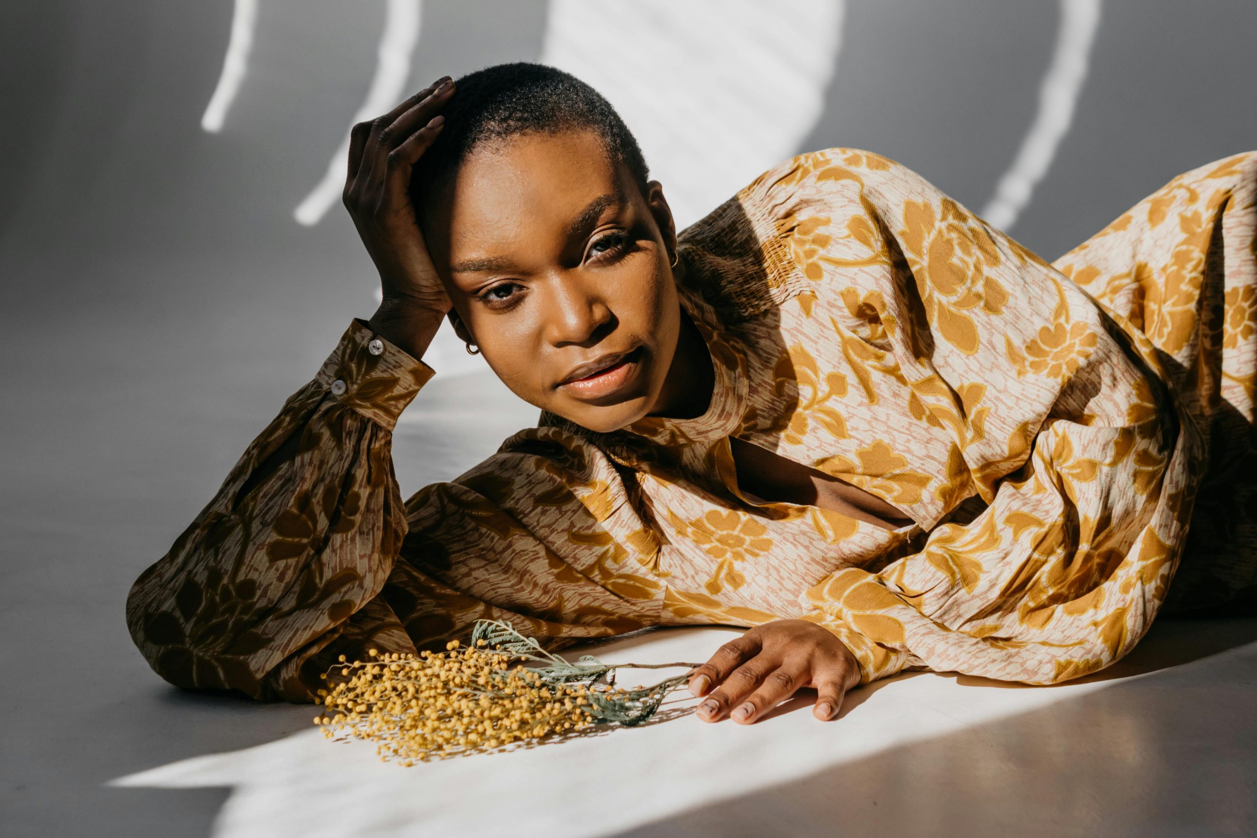 Photograph of Black Woman with short cropped afro hair, lying on studio floor