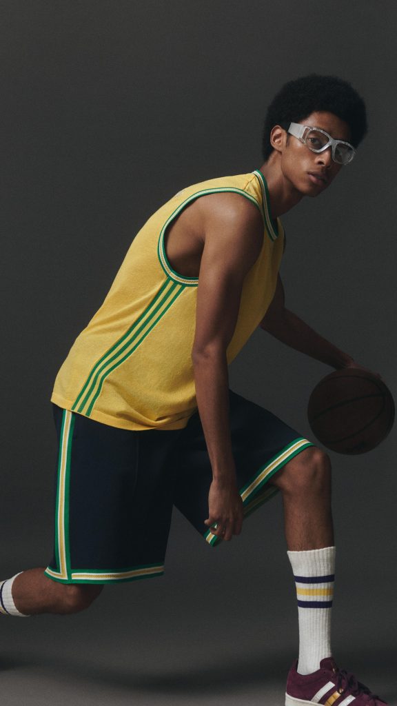 Model poses with afro, glasses and basketball gear with Adidas Three stripe detail
