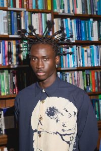Photograph of male model with silk wrap hair style at Fashion week.