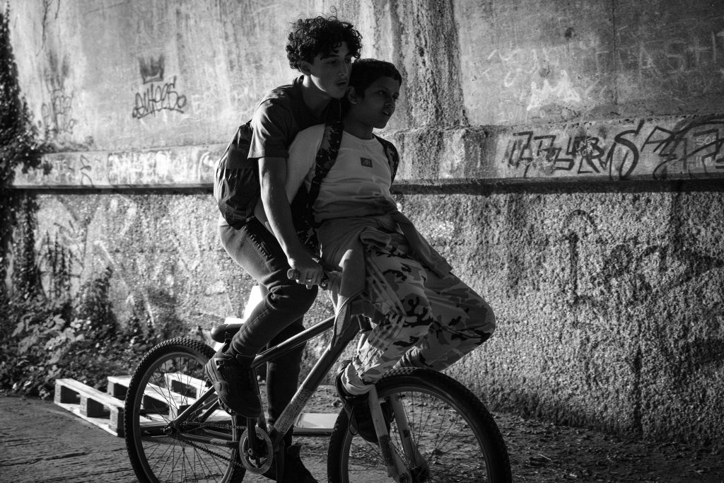Photograph of two 12 year old boys sharing a bicycle. Riding in the summer holidays. Screen grab from movie Ish, released in cinemas in July 2026. Photograph by Lara Cornell.